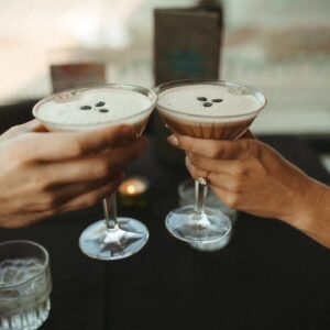 two people hold espresso martinis and cheers