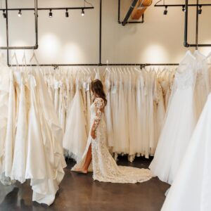 bride walks through aisle of dresses