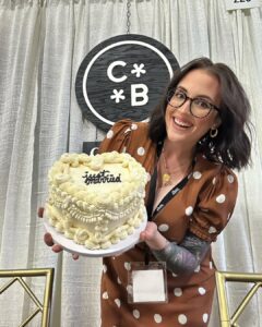 owner of Cake Baby poses, holding "Just Married" cake